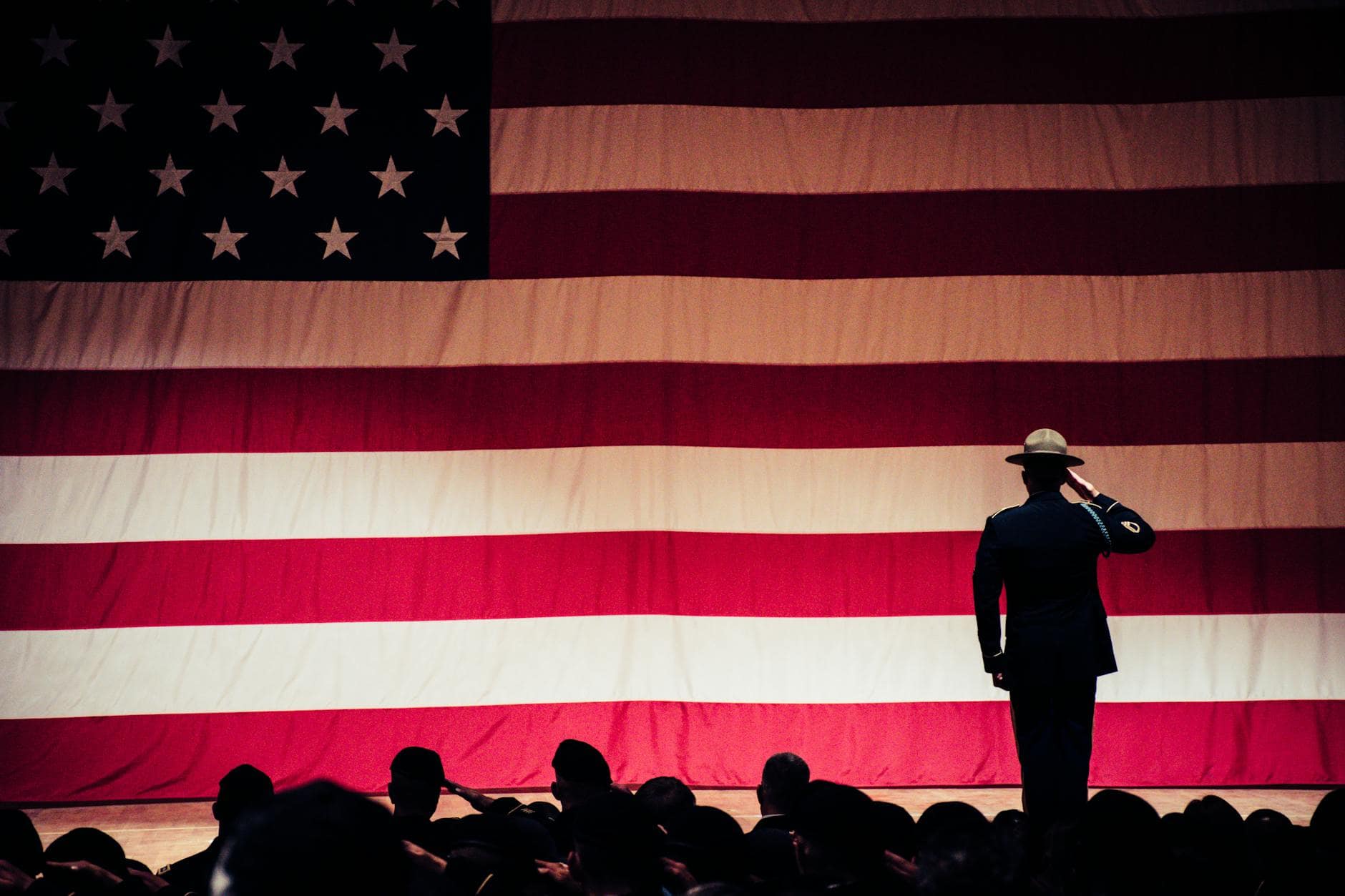 Memorial day- man standing on stage facing an american flag