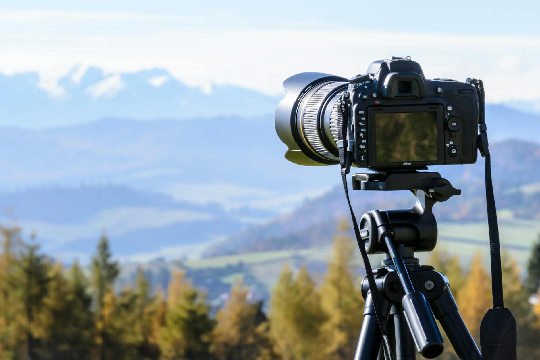 black dslr camera mounted on black tripod- essential gear for landscape shot